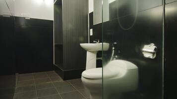A modern bathroom with a toilet, sink, and glass partition.