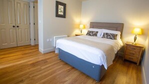 A bedroom with a bed, bedside lamps, a heater, and a door. - The Cherry Tree Rochford (Rochford)