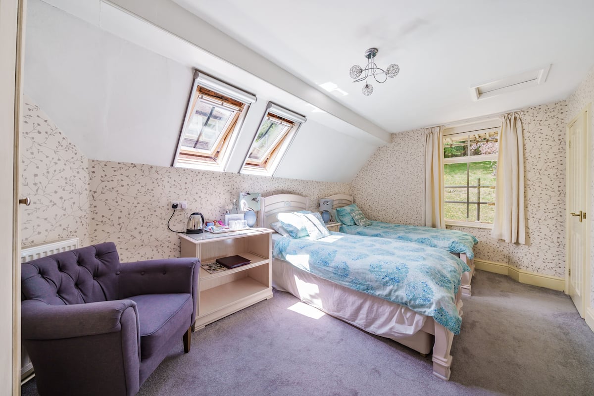 A bedroom with a bed, a chair, a nightstand, and a window.