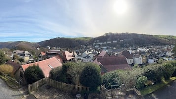 A town with traditional architecture, a clear sky, and a view of hills in the distance.