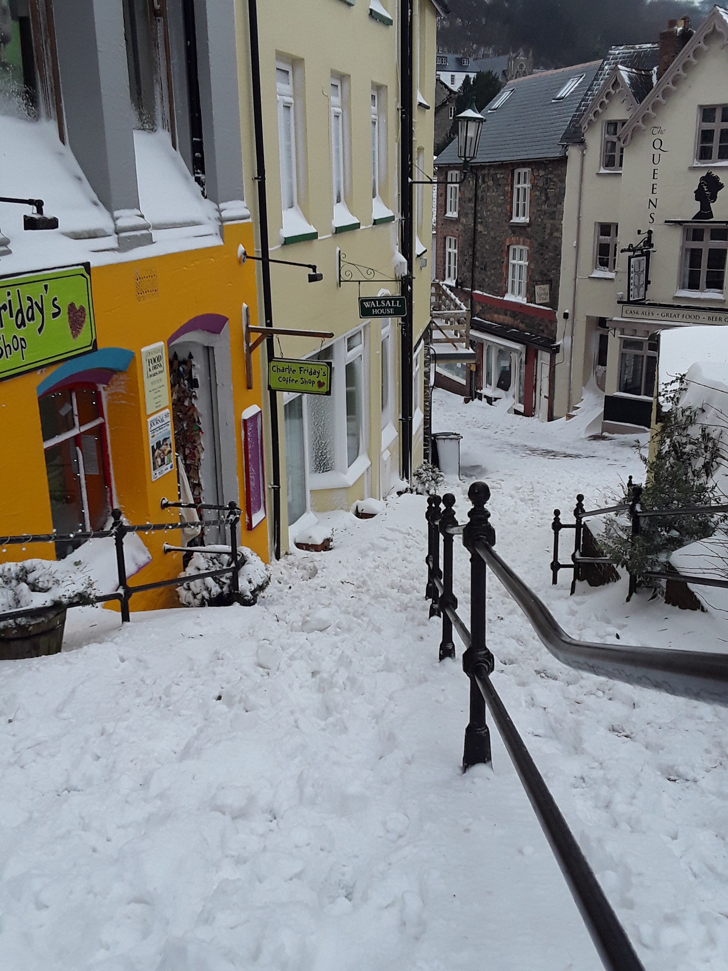 A snow-covered street with buildings, including a shop with a sign that reads 'WALSALL HOUSE.'