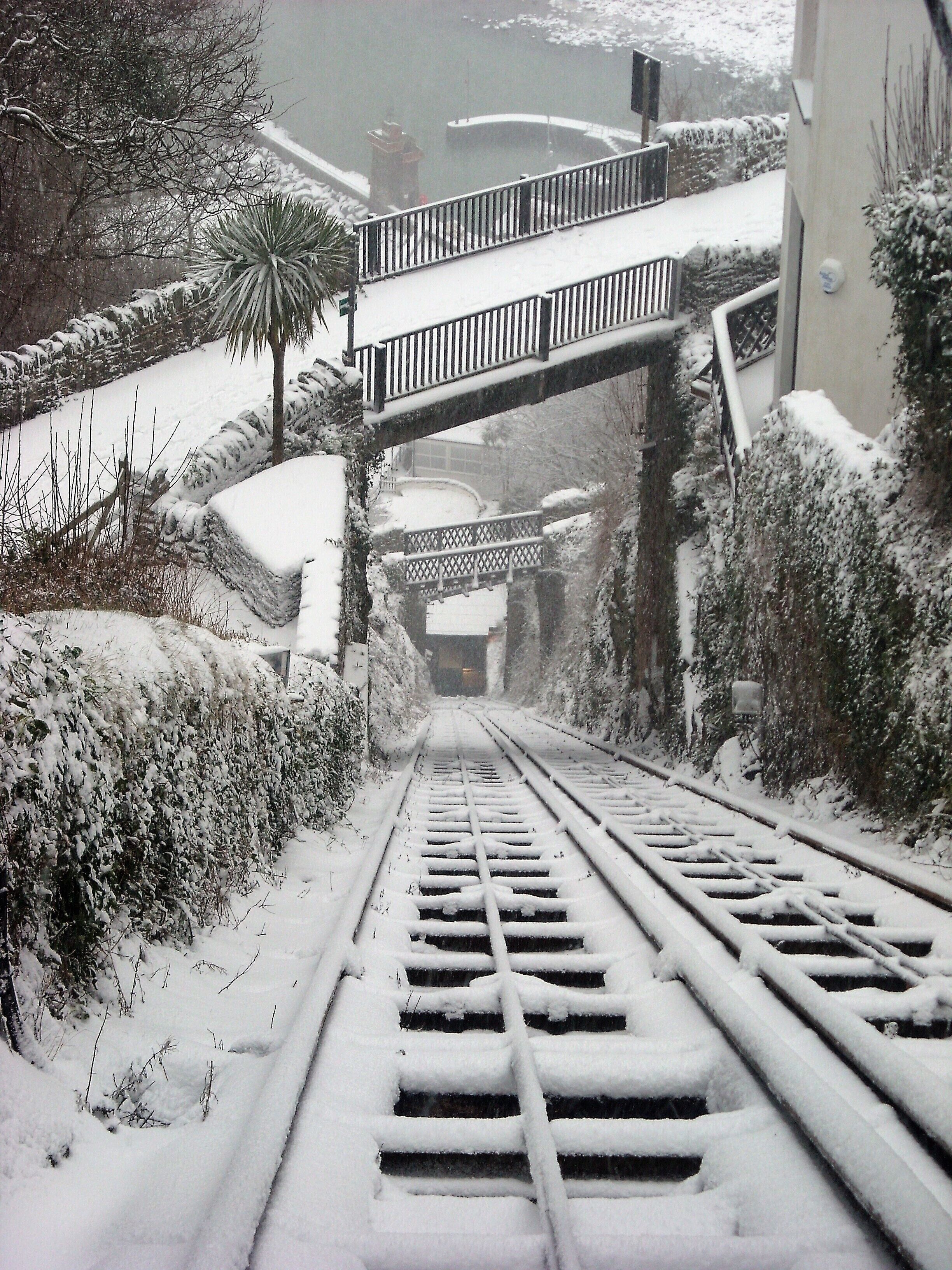 Une voie ferrée recouverte de neige, avec un pont piétonnier enjambant la voie.