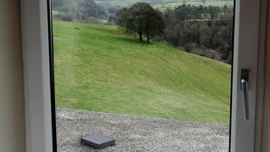 A view from a room with a door, overlooking a grassy hill with a tree and distant fields. - Lathkil Hotel (Bakewell)