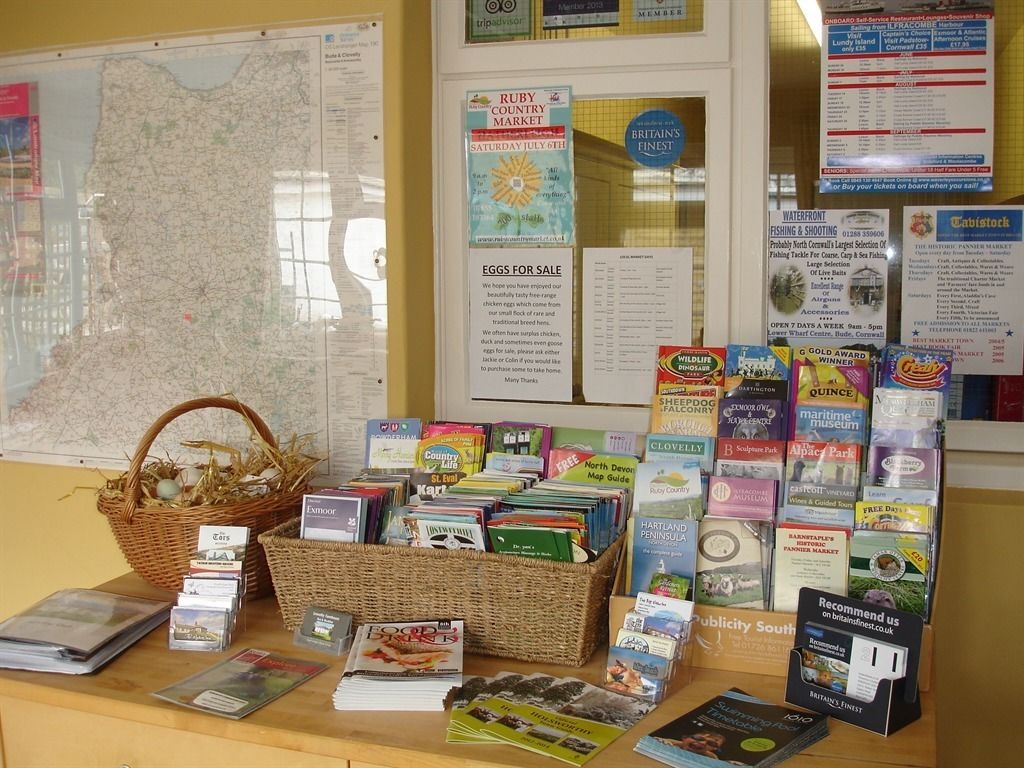 A display of travel books and maps, including a map of Cornwall and a basket of brochures.