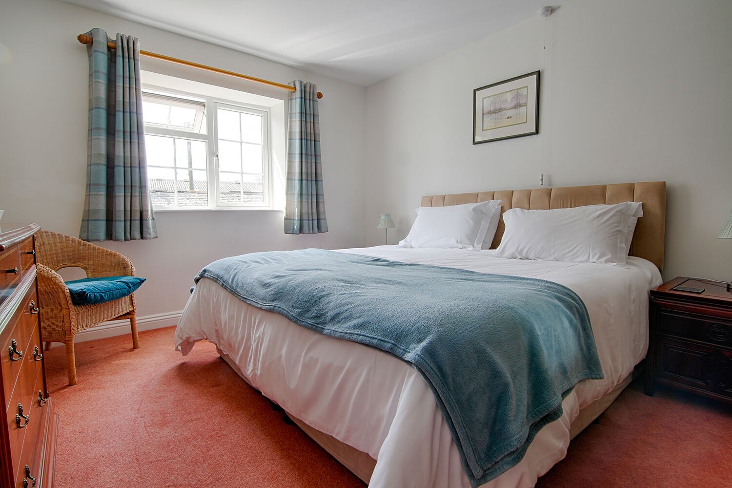 Une chambre à coucher avec un lit, une chaise, une commode et une fenêtre avec des rideaux.