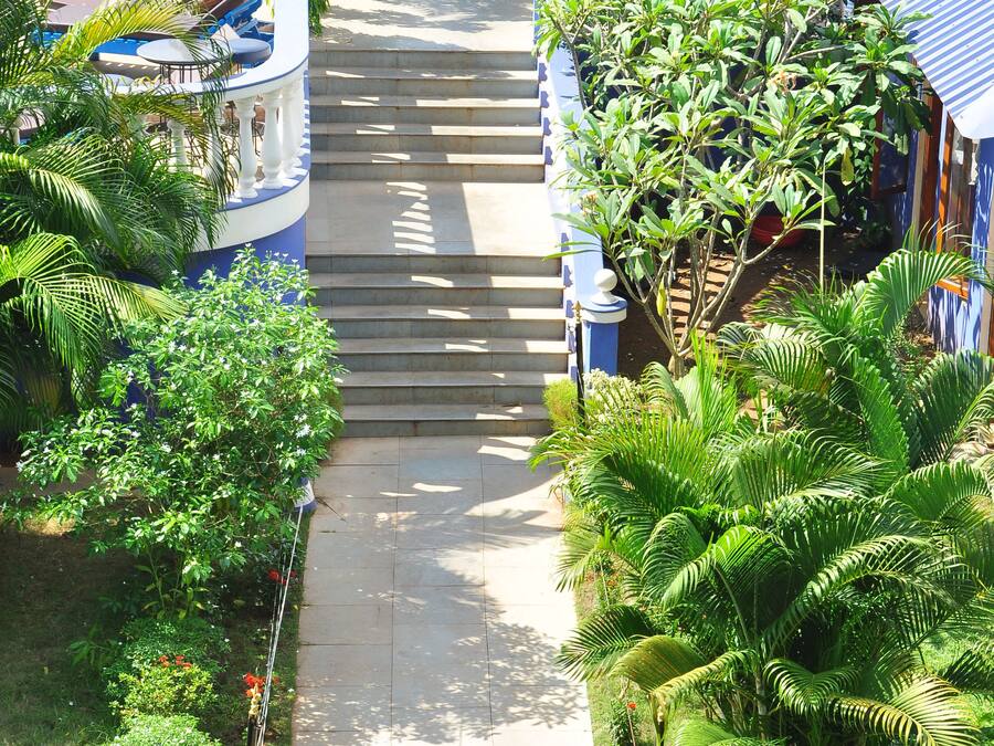 Un camino que lleva a un área de piscina con sillones de descanso y una escalera.