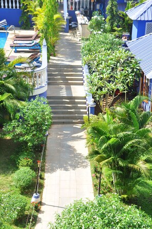 A pathway leading to a pool area with lounge chairs and a staircase. - Mayflower Beach Resort (Baga)