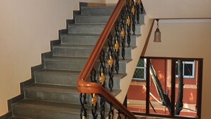 A staircase with a wooden handrail and black balusters with golden accents.