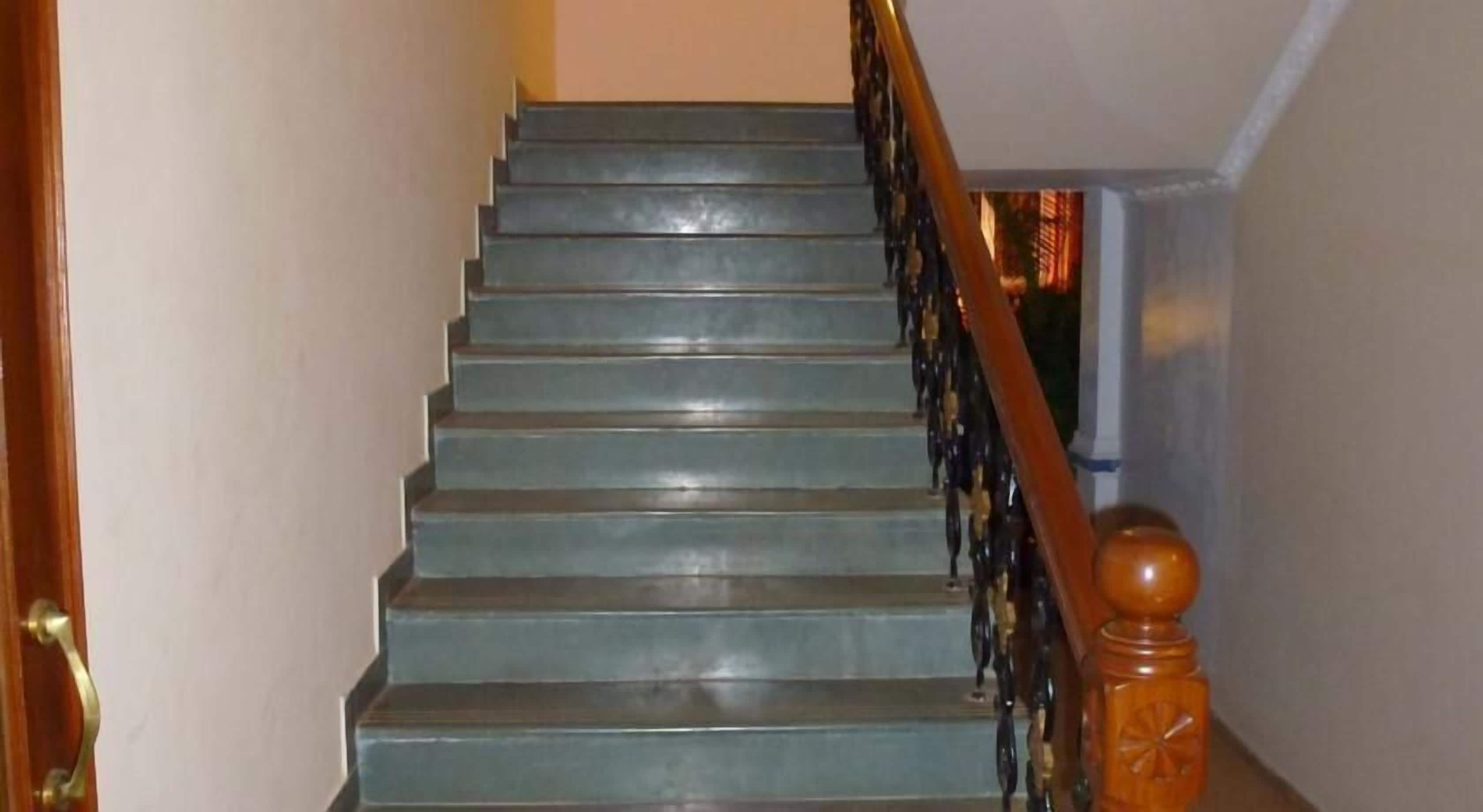 Un escalier avec une main courante en bois et une balustrade en métal.