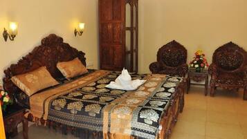 Quarto tradicional com uma cama grande, móveis de madeira detalhados e luminárias fixadas na parede.