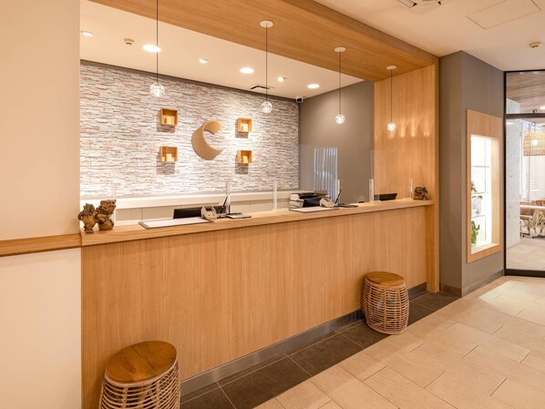 A reception area with a wooden counter, stone wall, and modern pendant lighting.