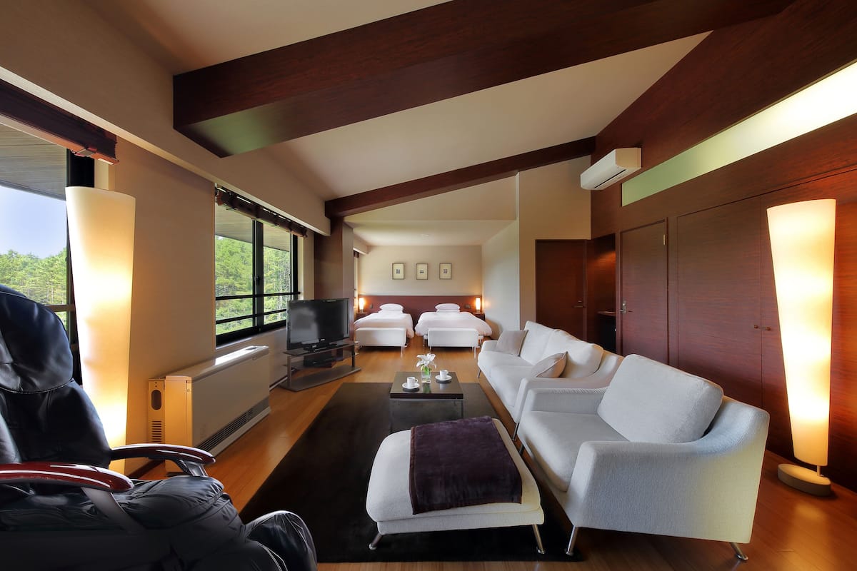A modern living room with a sofa, ottoman, and a television.