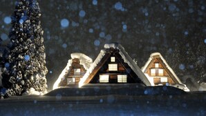 A snow-covered cabin with a steep roof and wooden walls, surrounded by snow and trees. - Hotel Ryu Resort and Spa (Takayama)