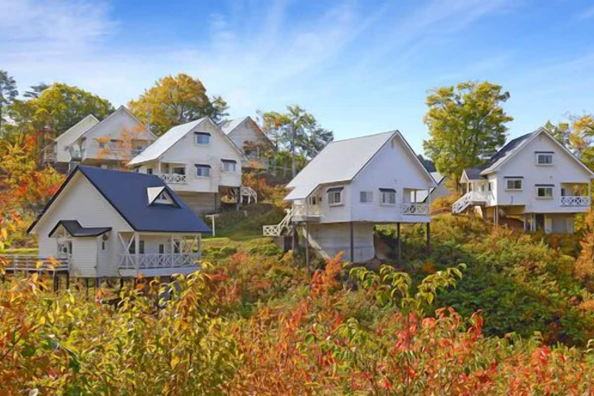 A cluster of white houses with gabled roofs, surrounded by autumn foliage.