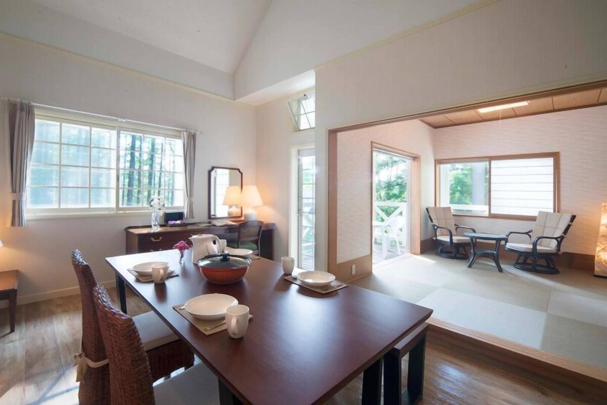A spacious dining area with a long table, chairs, and a view of the outdoors.