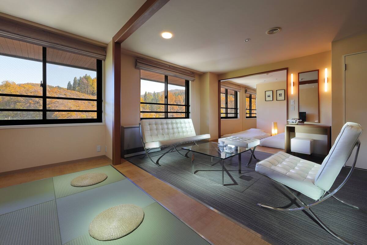 A modern room with tatami mats, a sofa, a glass table, and a chair.
