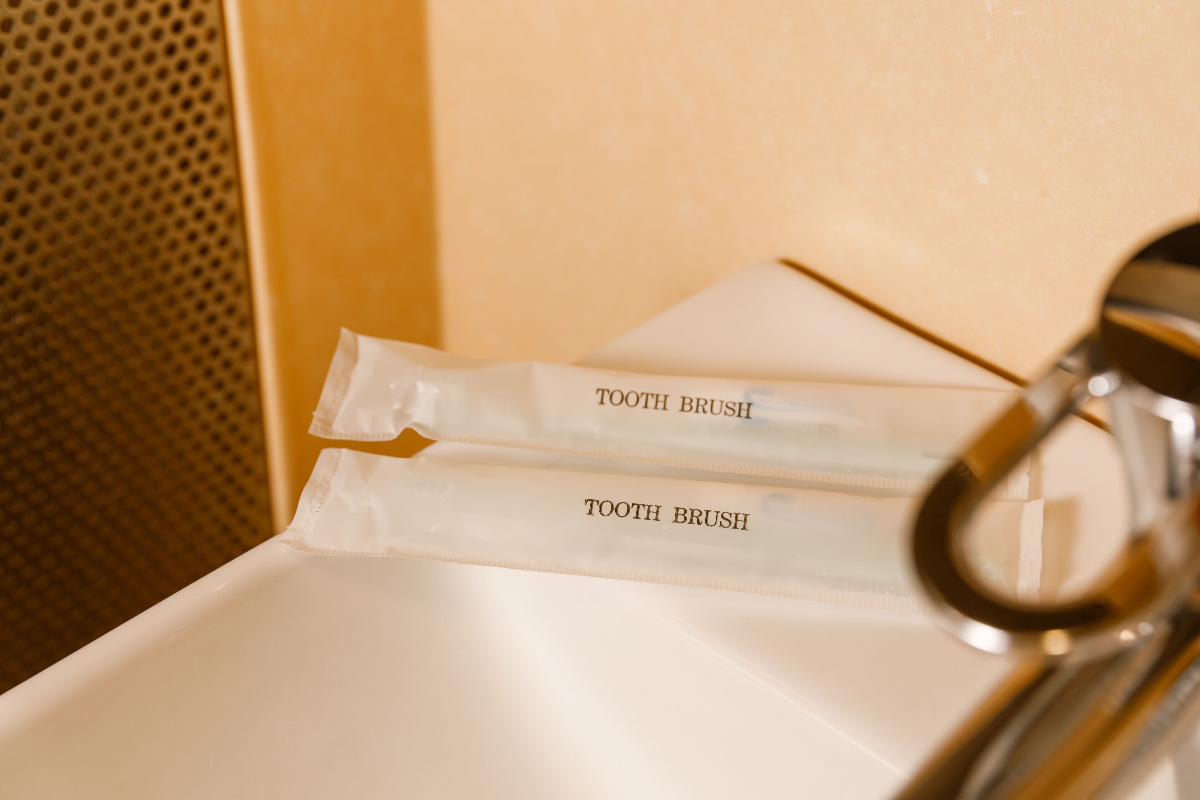 Two toothbrushes labeled "TOOTH BRUSH" placed on a white sink.