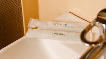Two toothbrushes labeled "TOOTH BRUSH" placed on a white sink.