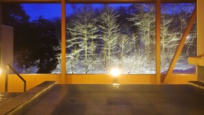 A room with a large window overlooking a snowy forest at dusk. - Hotel Ryu Resort and Spa (Takayama)