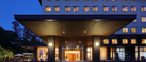 A modern hotel entrance with a covered walkway, glass doors, and multiple windows.