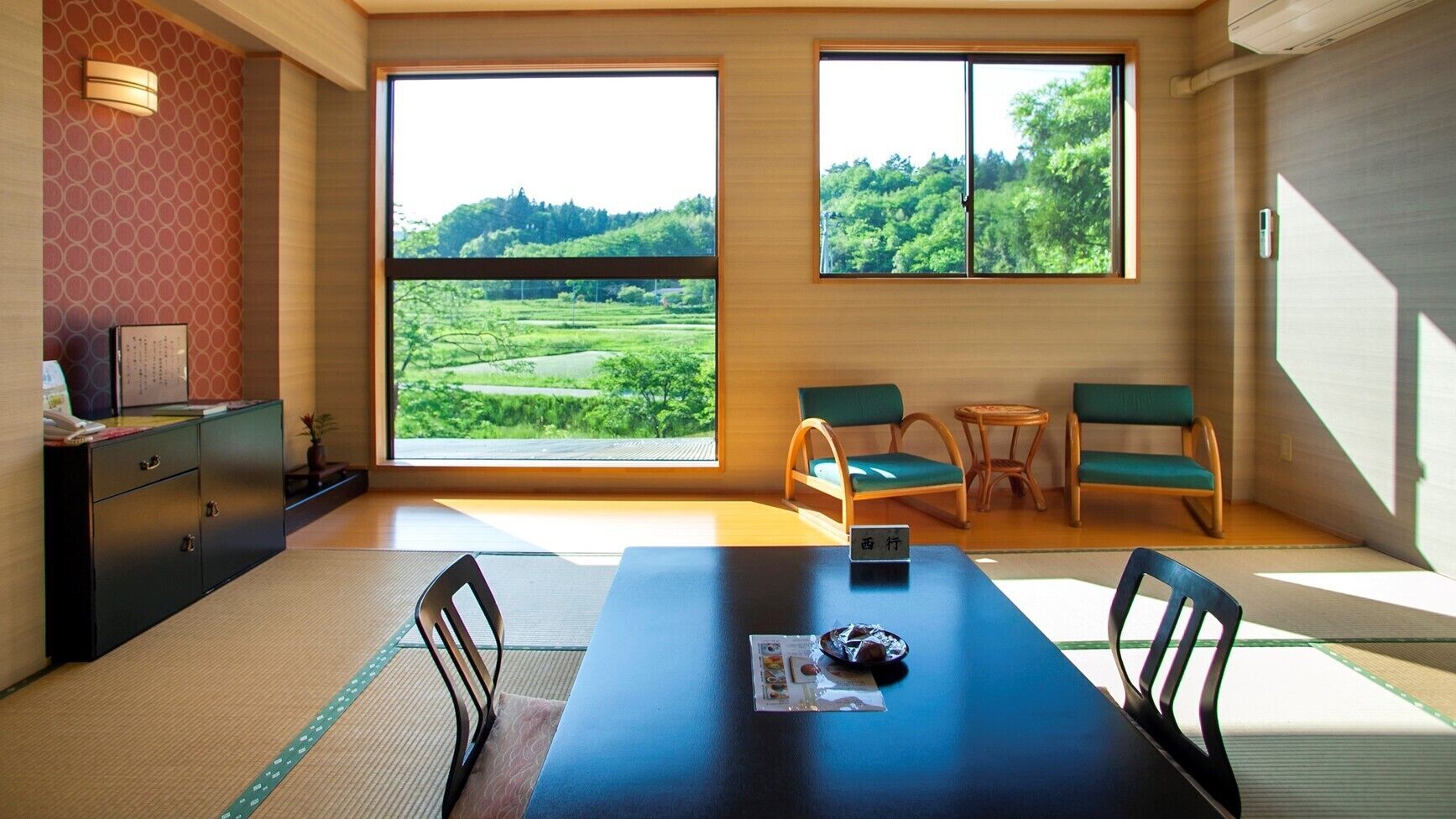 Um quarto com uma grande janela, uma mesa de jantar, cadeiras, um pequeno armário e um tatame.