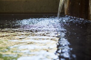 Primer plano de agua fluyendo sobre una superficie reflectante, creando ondas y reflejos de luz.
