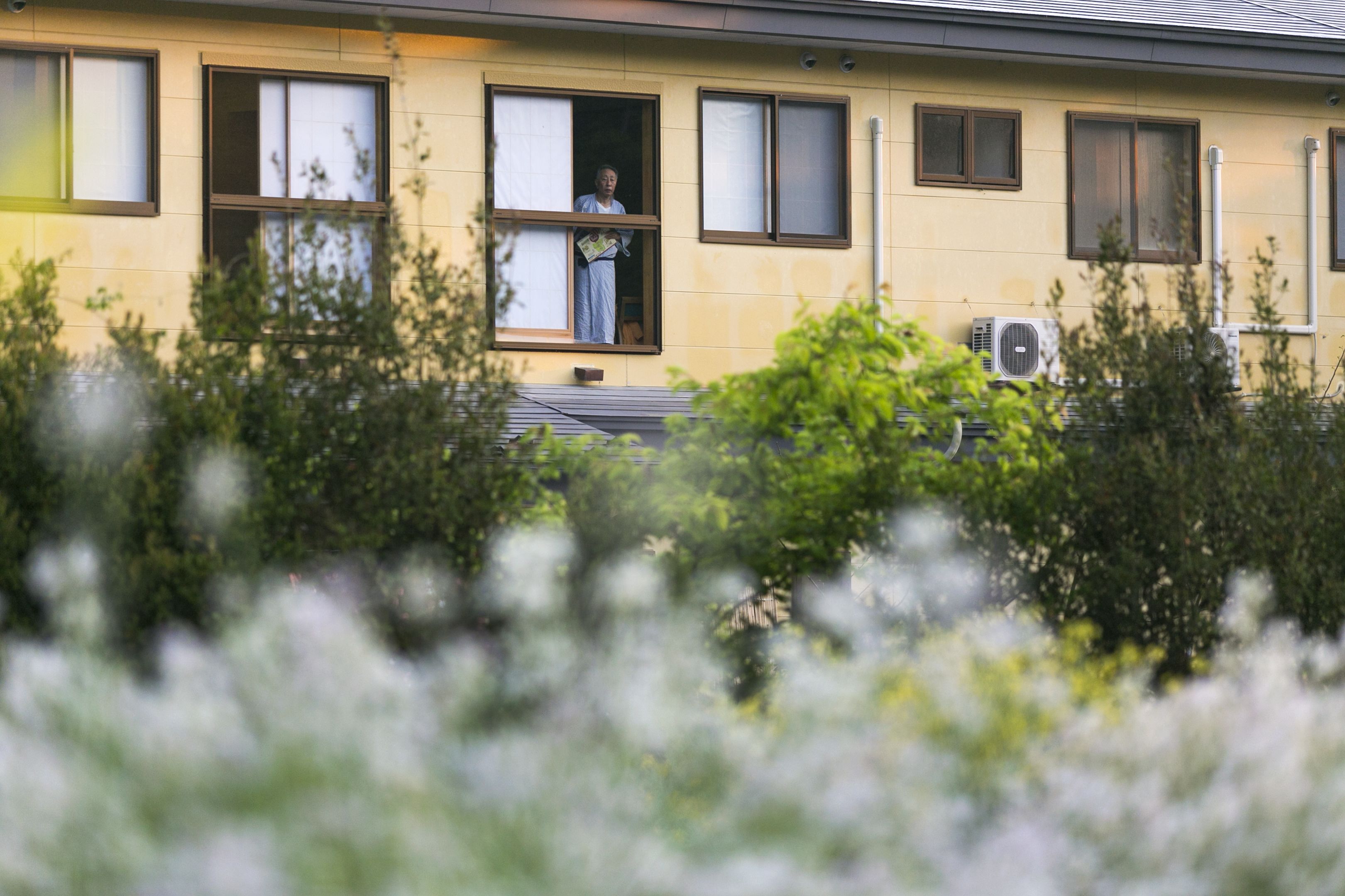 A yellow building with multiple windows and an air conditioning unit on the side.