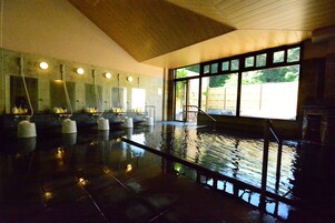 Una amplia piscina cubierta con varias pistas de natación, techo de madera y grandes ventanales que dejan entrar luz natural.