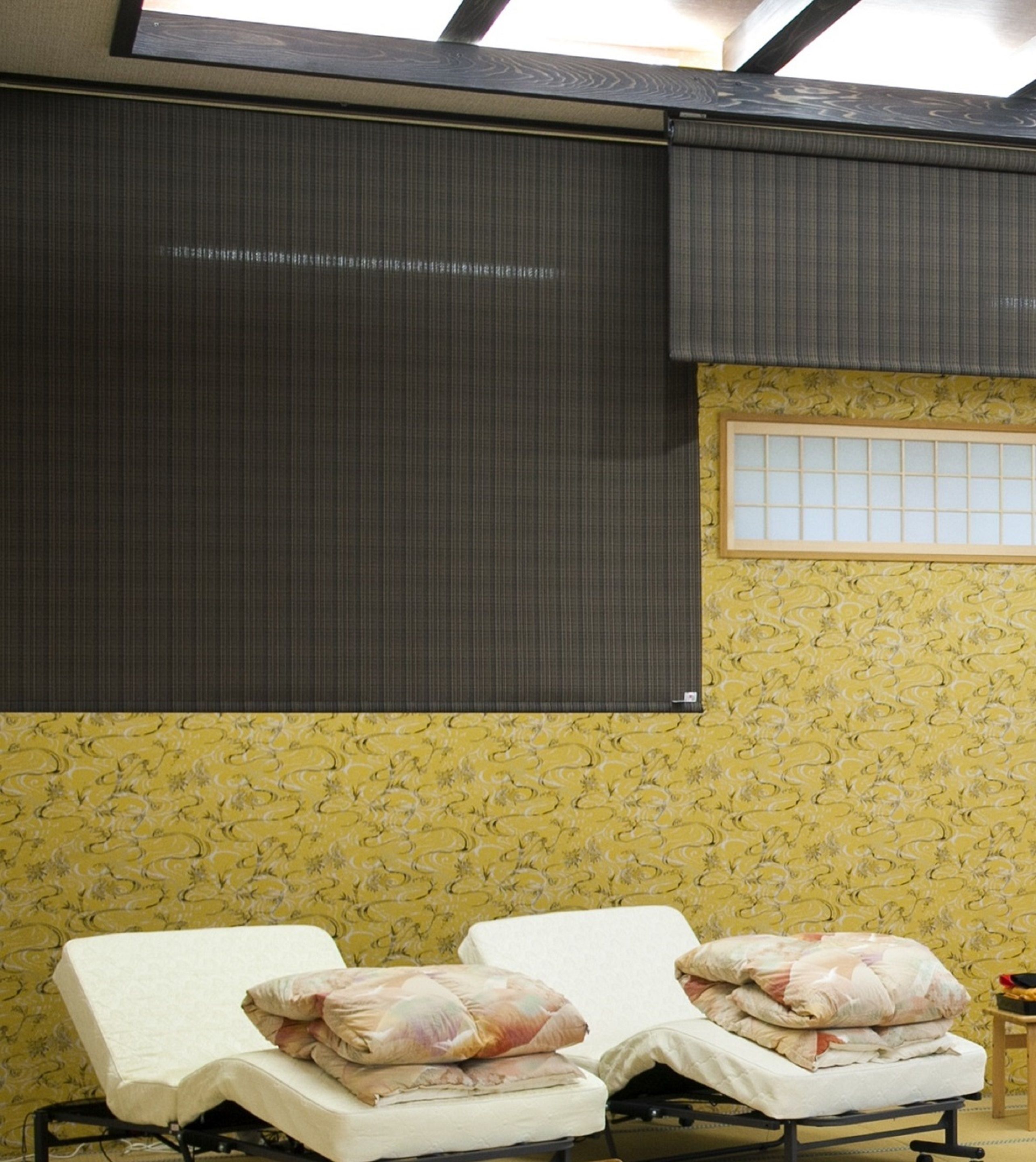 Deux lits simples avec des oreillers, une fenêtre et un mur décoré de motifs.