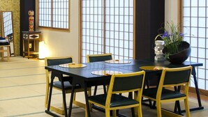 A traditional Japanese-style room with tatami flooring, a low table with chairs, and shoji screens.