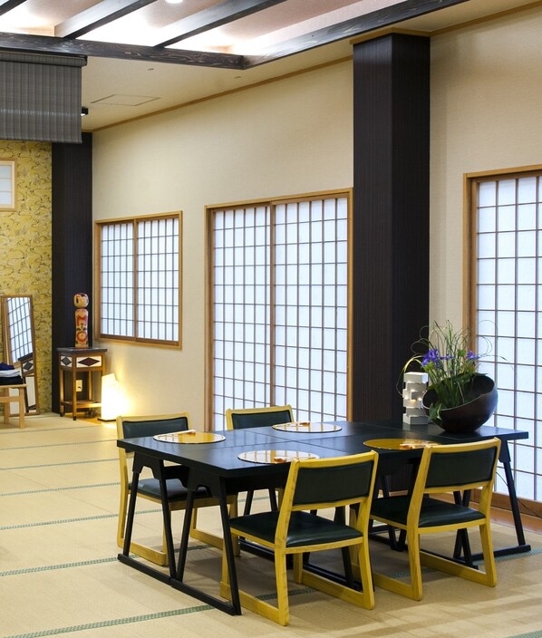 Una habitación tradicional japonesa con suelo de tatami, una mesa baja con sillas y puertas correderas shoji.