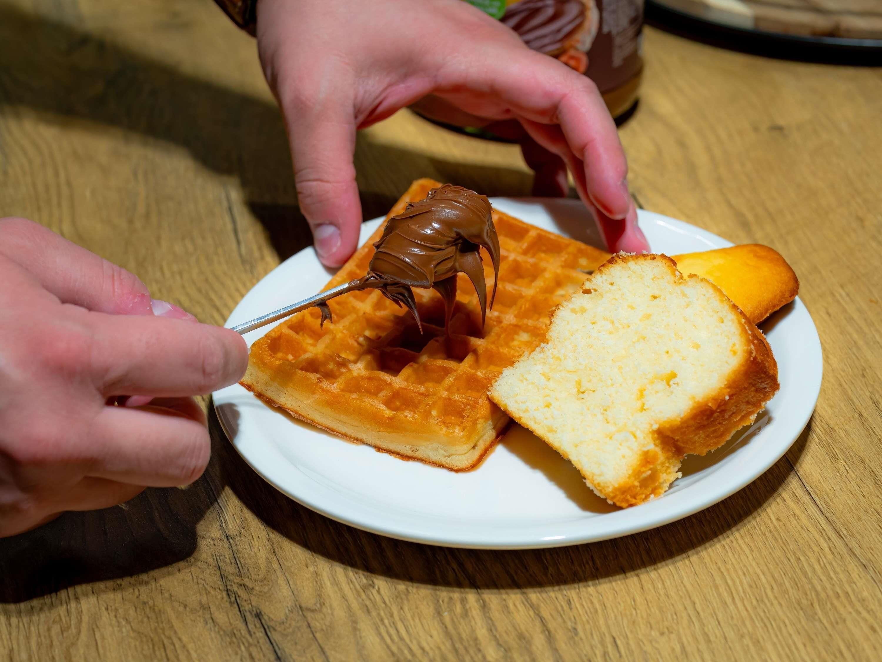 Une assiette avec un gaufre, une tranche de pain grillé et un produit enrobé de chocolat.