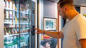 Un homme est en train d’utiliser un distributeur automatique rempli de collations et de boissons.