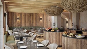 A modern restaurant with wooden panel walls, a central bar area, and a variety of seating options including booths and tables. - Al Nin Hotel&Spa (Livigno)