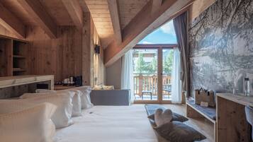Een houten interieur met een bed, kussens, een bureau en uitzicht op het landschap.