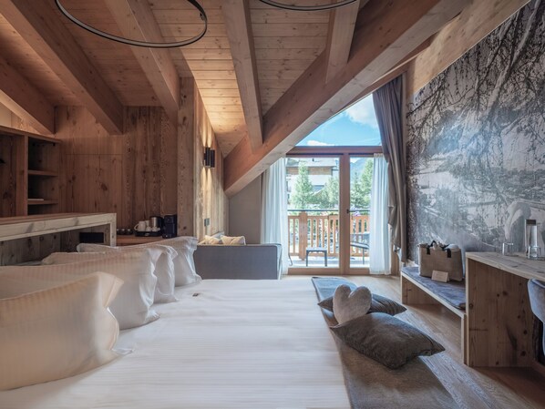 A wooden interior with a bed, pillows, a desk, and a view of the outdoors. - Al Nin Hotel&Spa (Livigno)