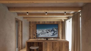 A modern interior with a wooden bar area, a large TV mounted on the wall, and a view of snowy mountains. - Al Nin Hotel&Spa (Livigno)