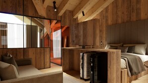 Ein moderner, rustikaler Raum mit Holzbalkendecke, einem Bett mit Kissen, einem Sofa, einem Schreibtisch mit Stuhl und einem großen Fenster.
