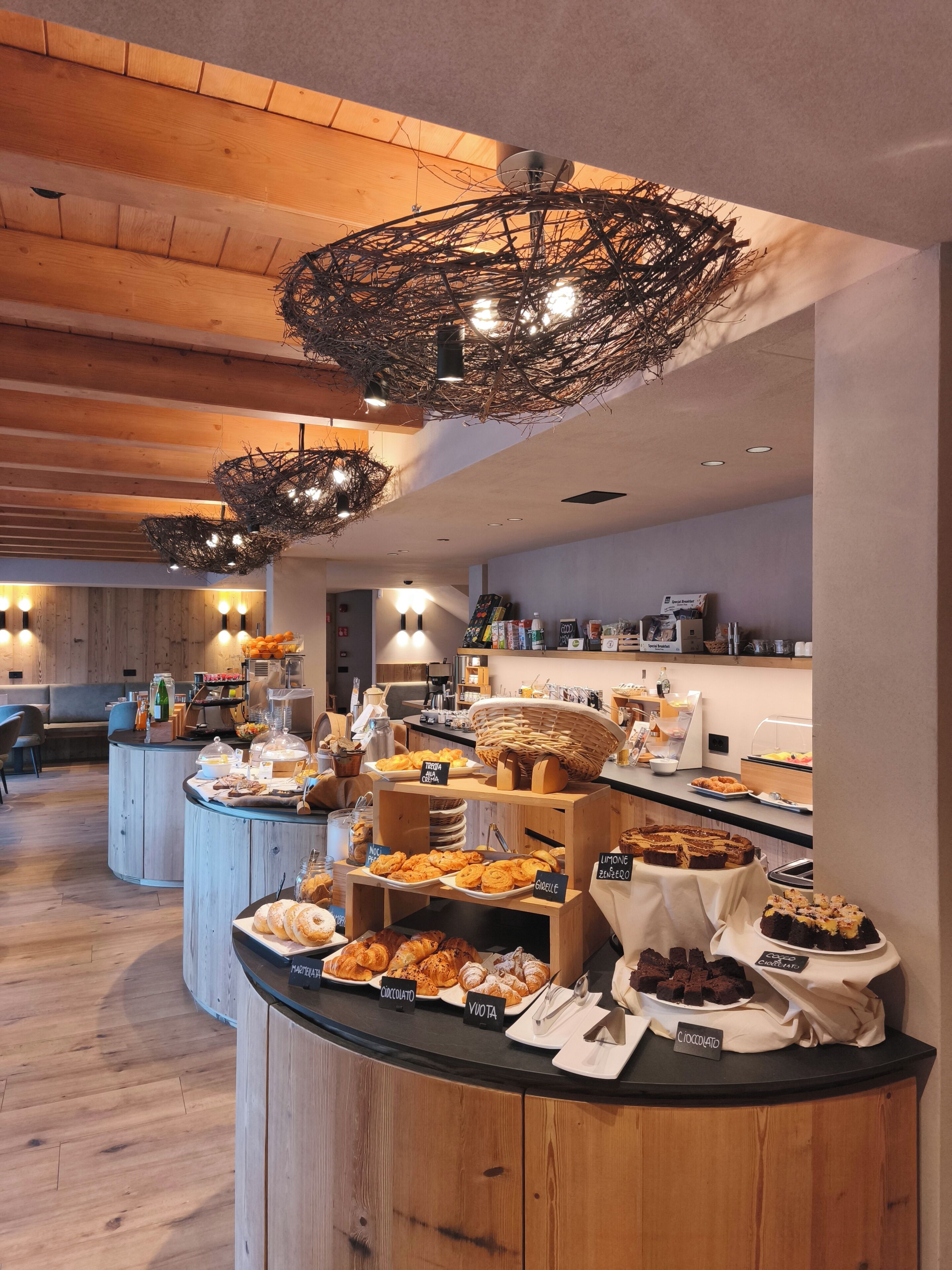 A buffet area with various food items and a wooden ceiling with hanging light fixtures.