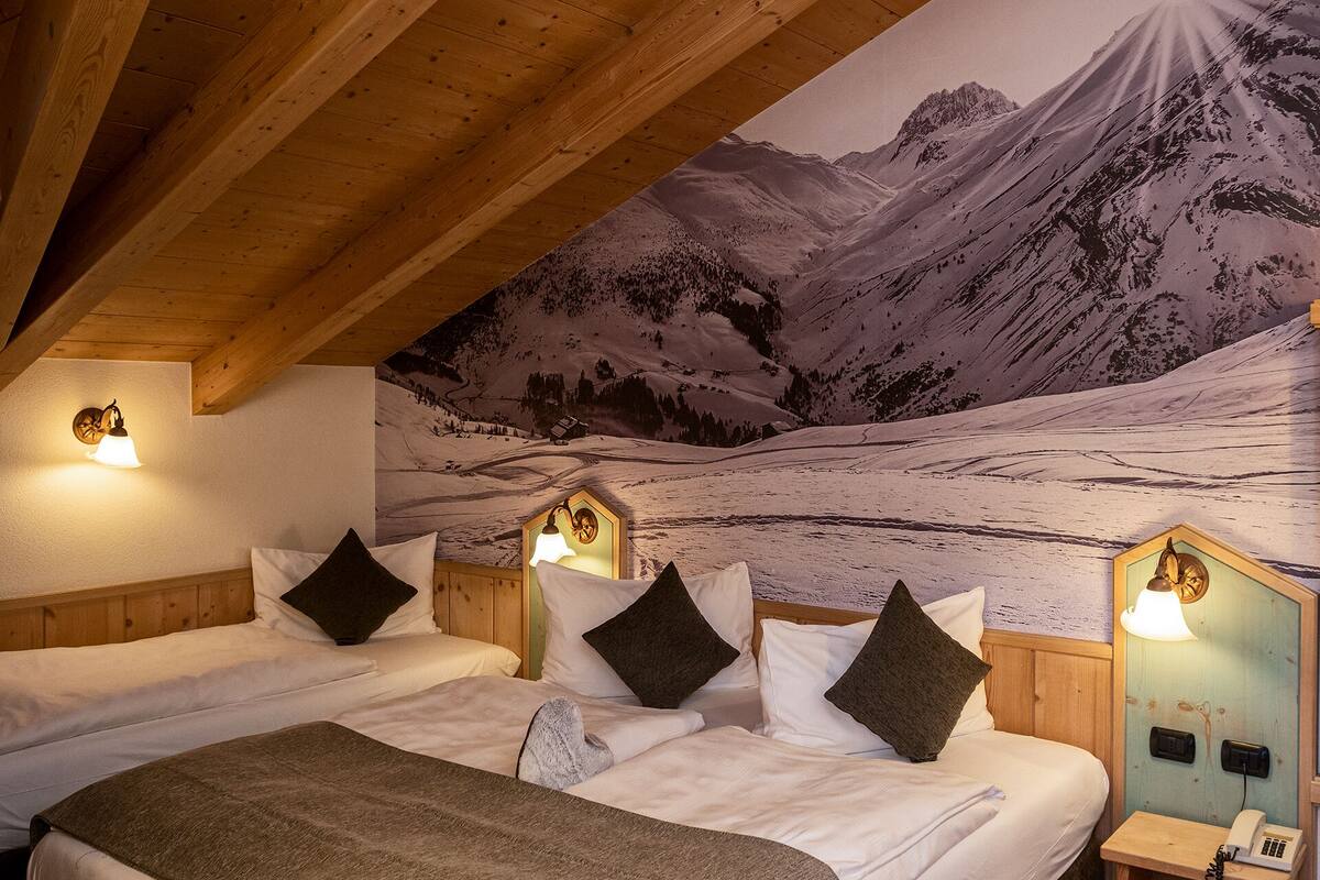 Un dormitorio con dos camas, cabeceros de madera y un mural de una gran vista de montaña.