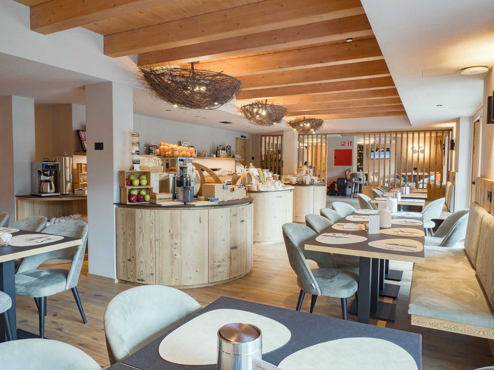 En modern restaurang med träbjälkar i taket, en central bardisk och sittplatser för gästerna.
