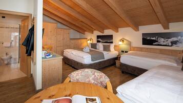 Un dormitorio acogedor en el ático con vigas de madera, dos camas, un escritorio pequeño y un baño.