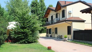 A two-story building with a balcony, outdoor seating, and a garden area. - B&B Villa Giglio (Arsago Seprio)