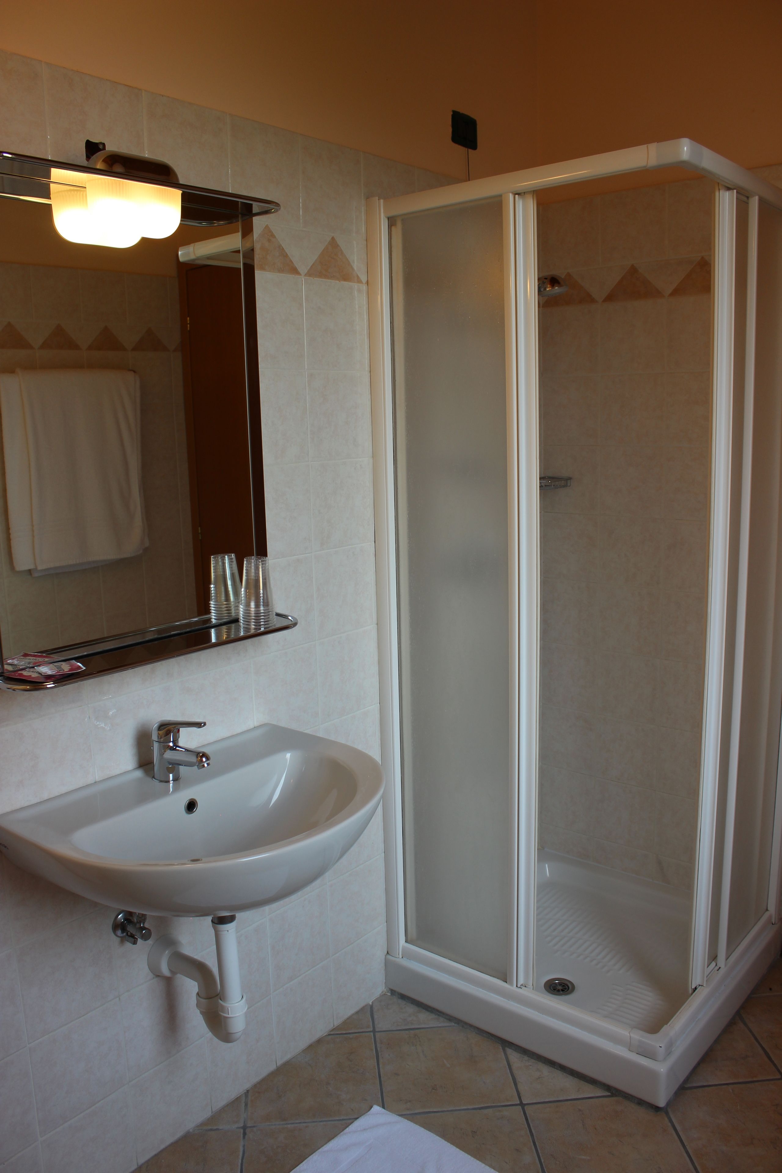 A bathroom with a white sink, mirror, and a glass-enclosed shower.