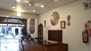 A reception area with a wooden counter, decorative wall art, a fire extinguisher, and a bulletin board.