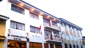 A hotel with a white facade, multiple balconies, and a flag.