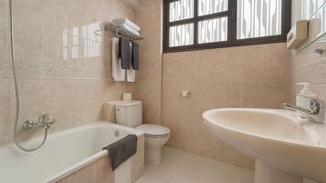 A bathroom with a bathtub, toilet, and sink.