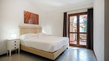 Un dormitorio con una cama, una mesita de noche, una obra de arte en la pared y vistas al balcón exterior.