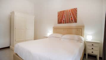 Un dormitorio con una cama grande, una mesita de noche, un armario y una obra de arte colgada en la pared.