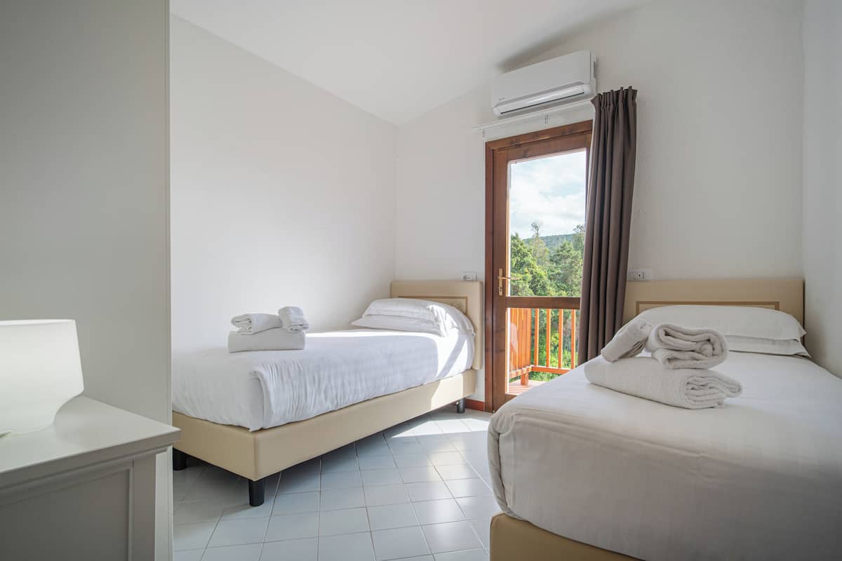 A hotel room with two beds, a balcony, and an air conditioning unit.